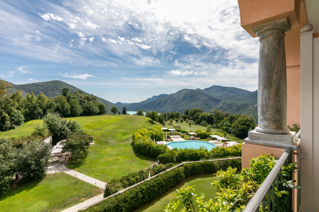 overlooking a wide green landscape with a swimming pool and mountains in the background