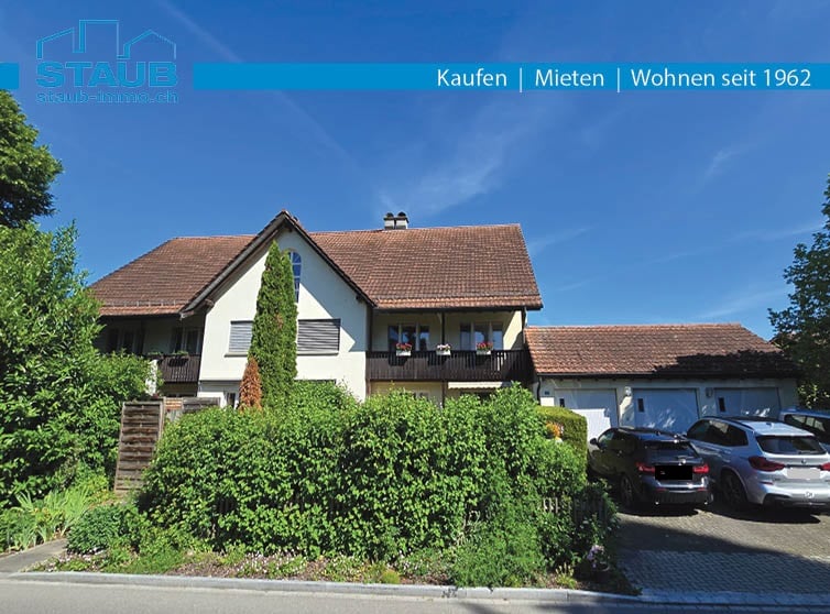 2 story house, brown roof, balcony, garage, green bushes, 3 cars parked