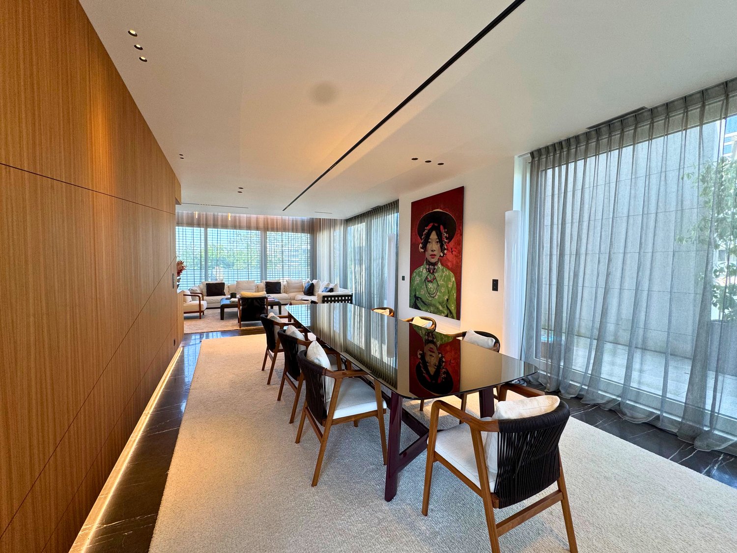 dining area with long table, modern wooden chairs, long curtains, artwork