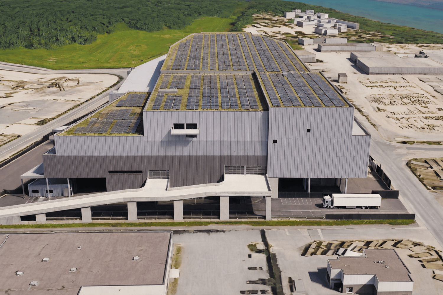 Industrial building, solar panels on roof, parking area, white truck