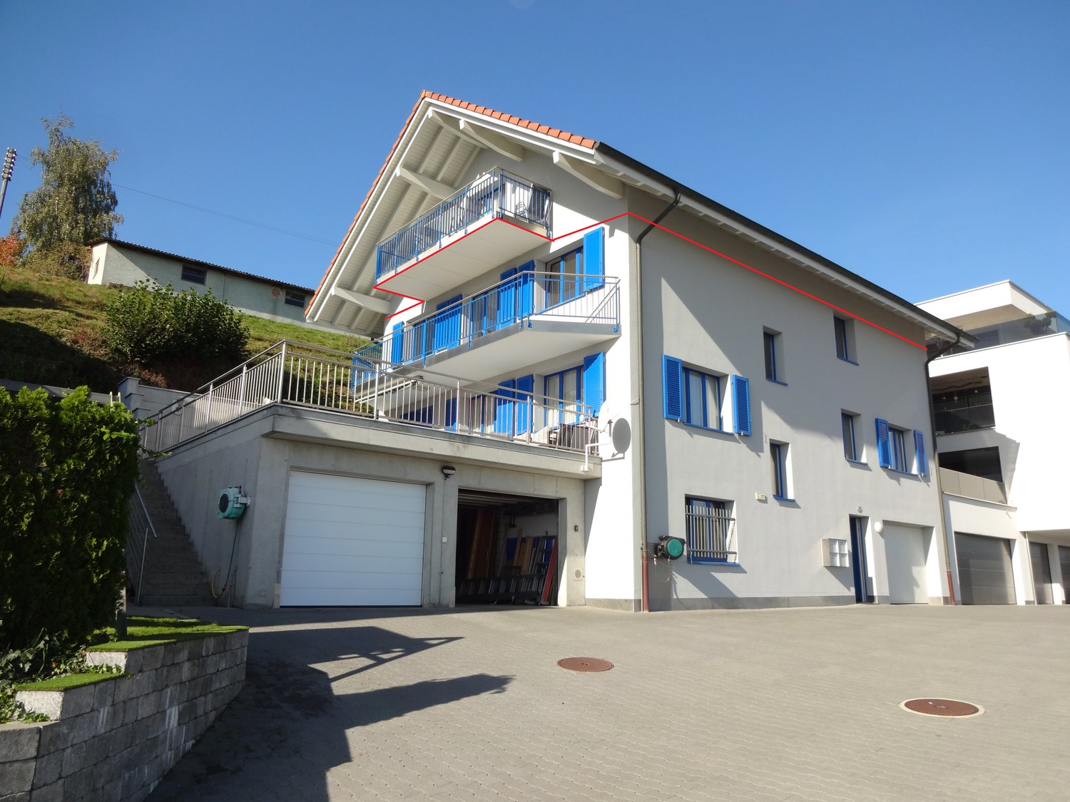 3-storey house, white walls, red roof, 3 garages, stairs, balconies, garage doors, shrubs, trees