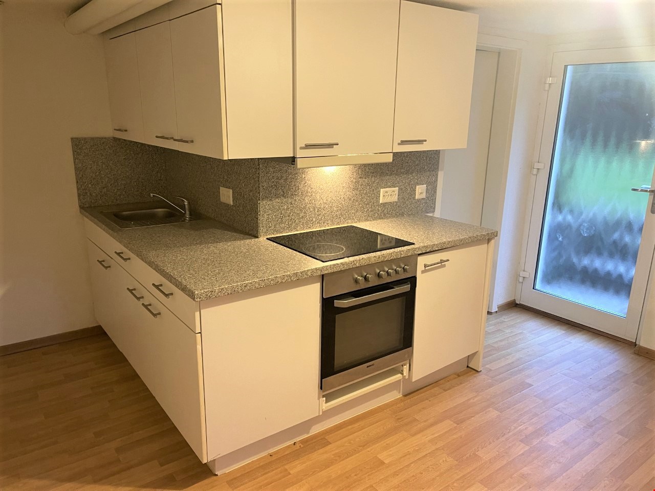 Modern kitchen with granite countertop, integrated stove, dishwasher, sink, and built-in cabinets