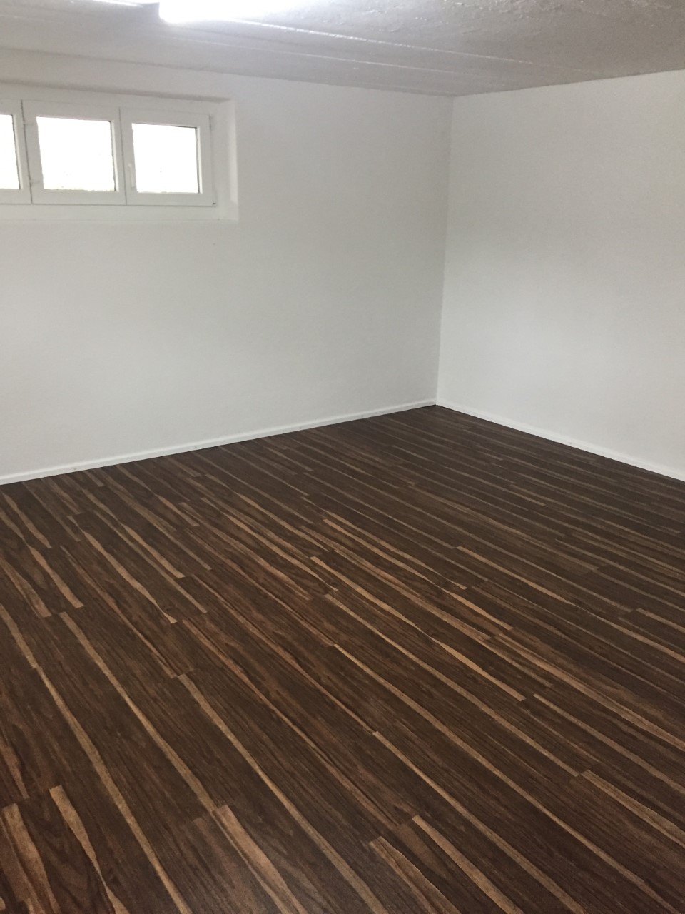 white walls, dark hardwood flooring, windows