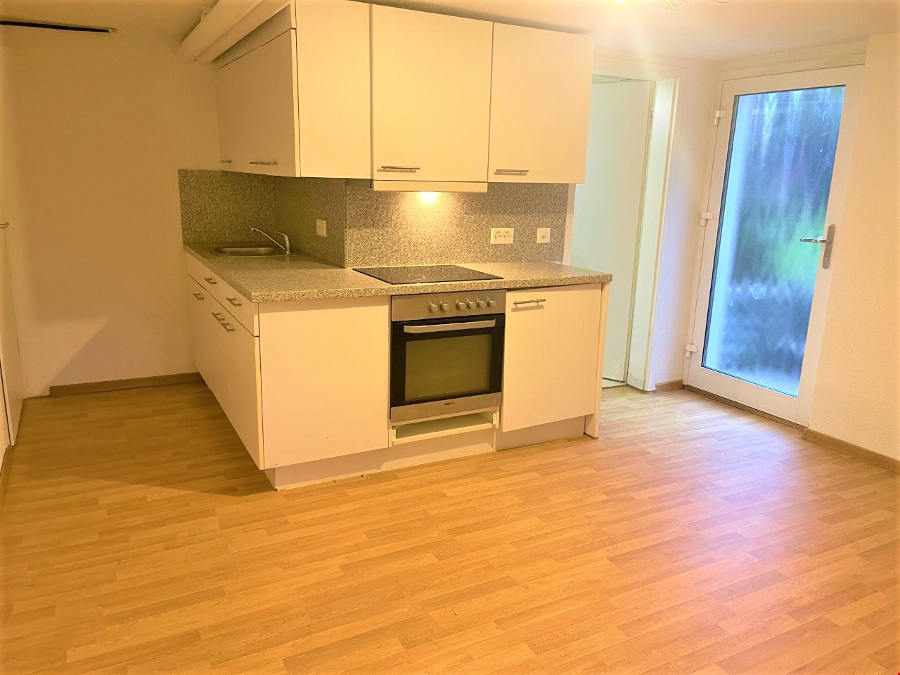 modern kitchen with white cabinetry, wooden floors, built-in oven, stainless steel sink, tiled countertop