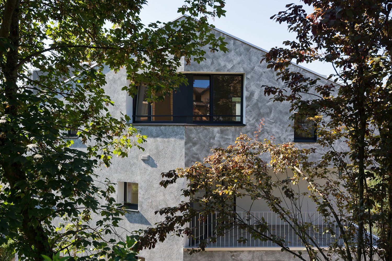 modern architecture, white exterior, large windows, balcony, positioned among trees