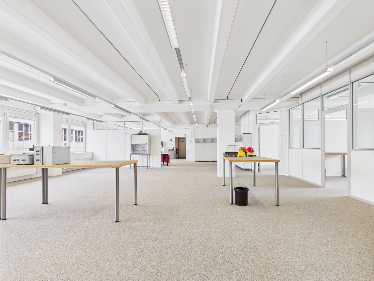 empty room, metal tables, trash bin, lamps, glass windows, white walls