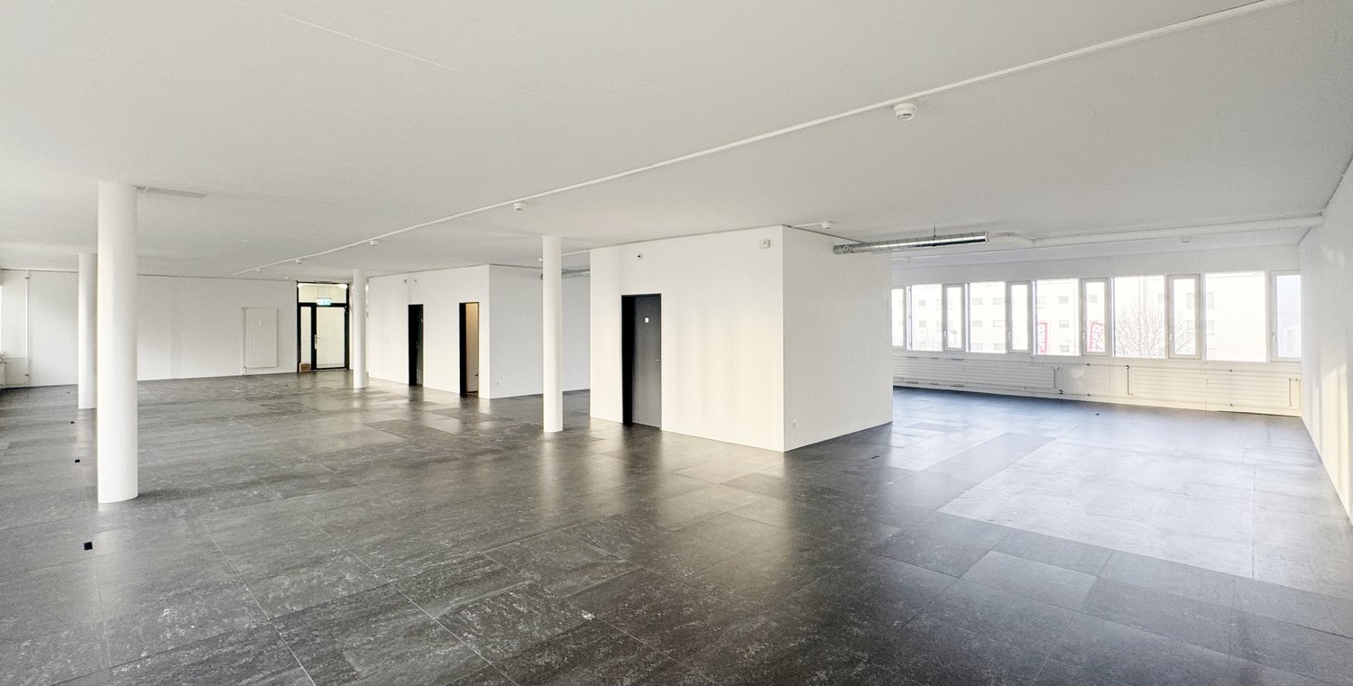 Empty room with tiled floors, white walls, four pillars, two doors, window grills.