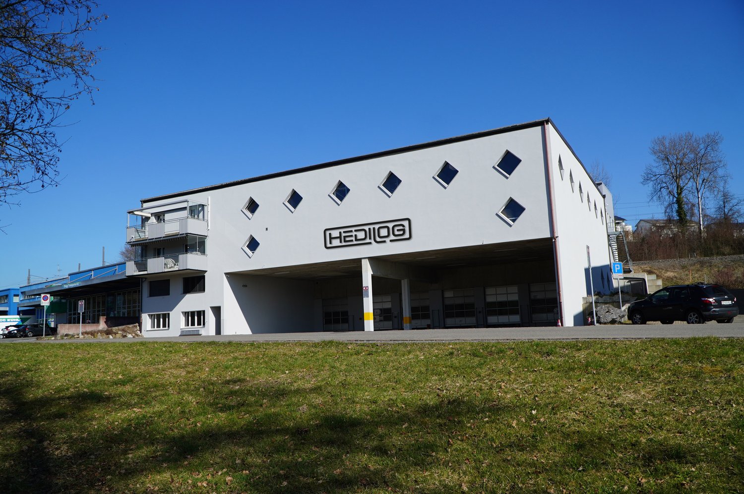 Single story white building, 5 garages, balcony on second floor