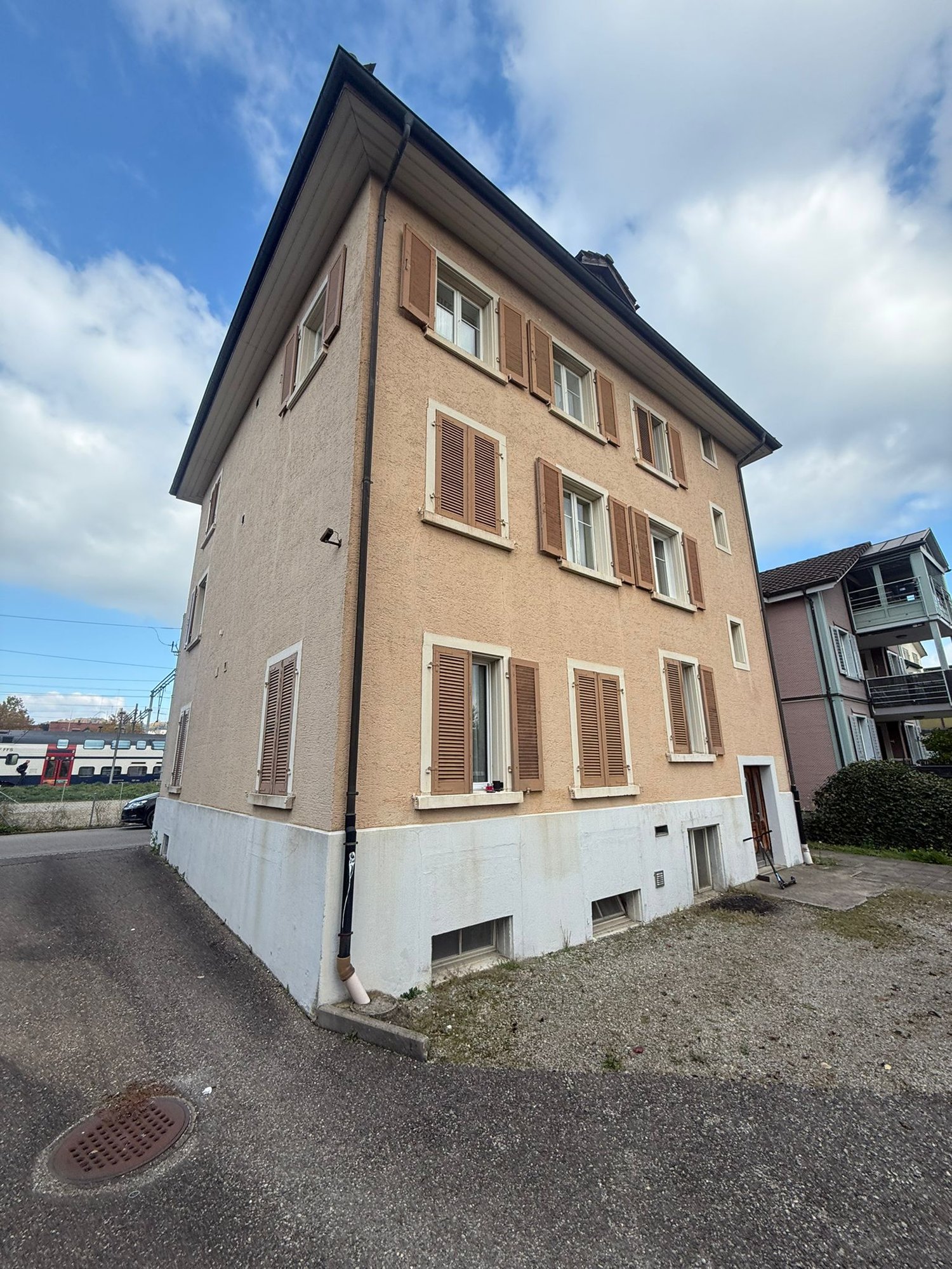 three story building, brown and white paint, multiple windows, two doors on ground floor
