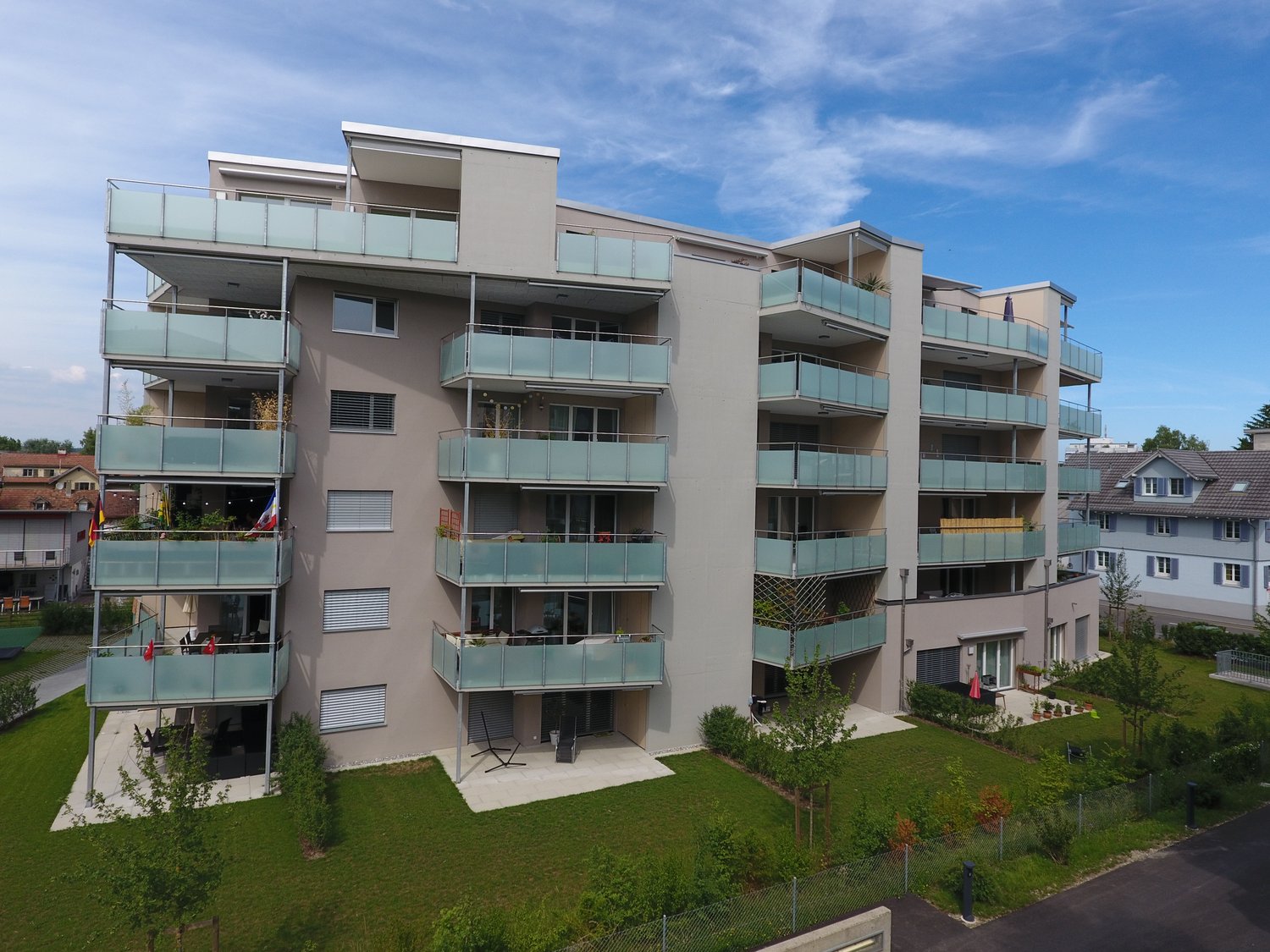 5-story apartment building with multiple balconies, modern design, surrounded by greenery