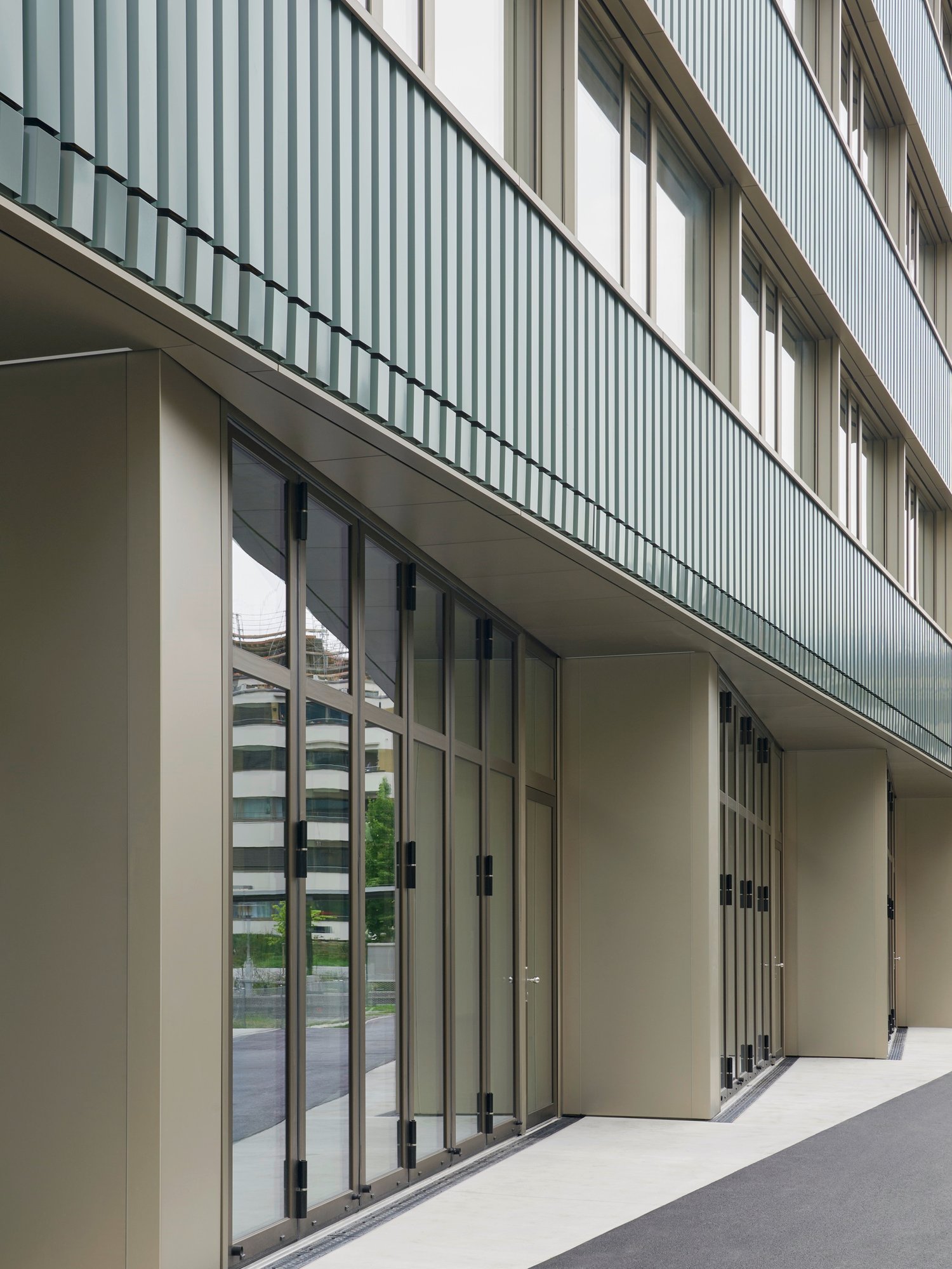 modern office building, glass facade, multiple floors, balcony with metal railings, wide entrance