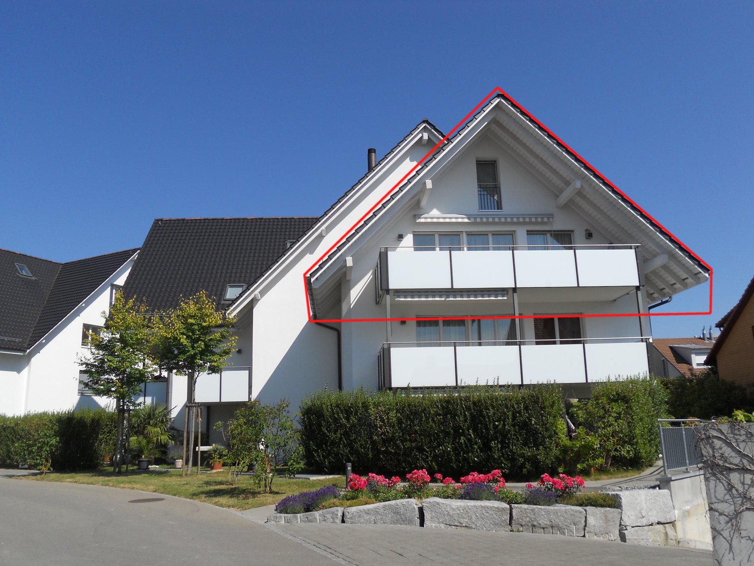 Detached house, white exterior, black roof, balcony, plants, fenced garden, driveway