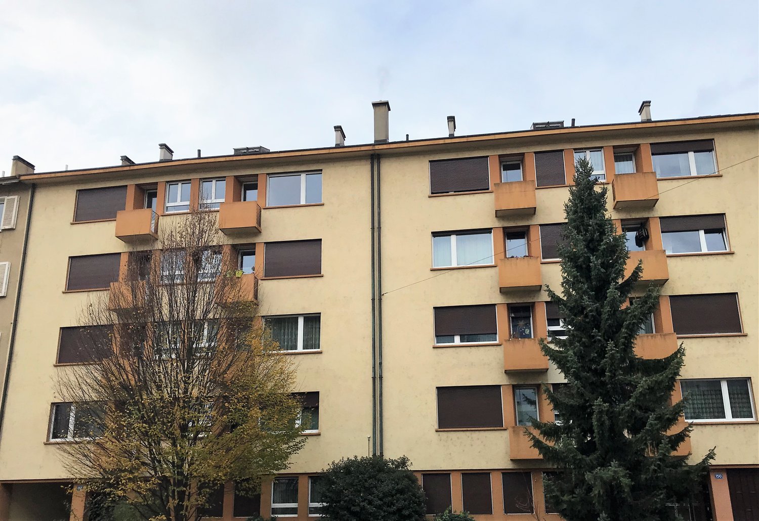 Apartment building, balconies, many windows, yellow walls, chimneys