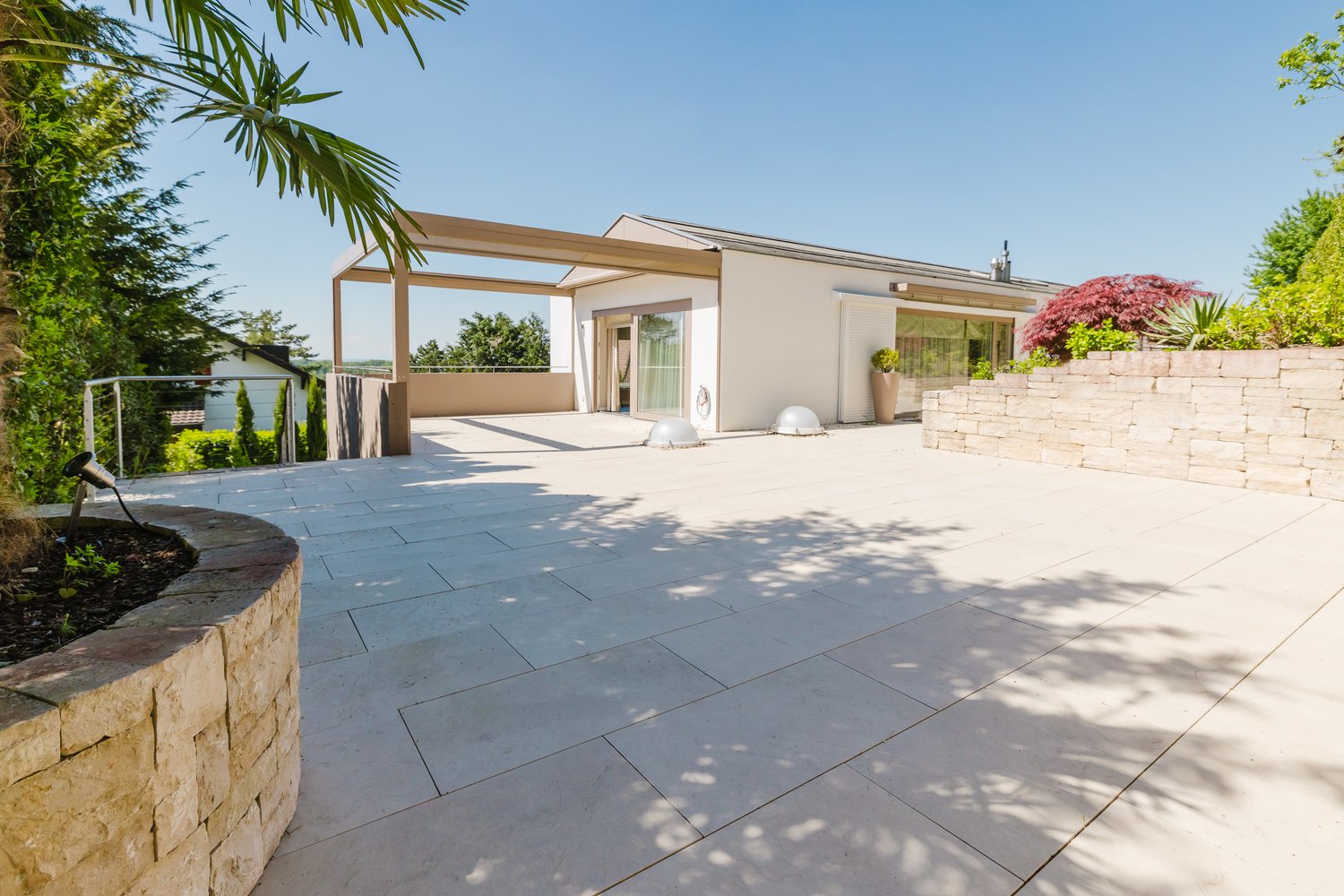 Contemporary single-family house, open terrace, modern architectural design, paved outdoor area, lush greenery, modern outdoor elements