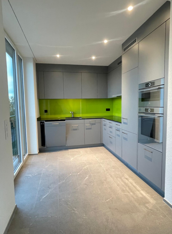 Modern kitchen, gray cabinets, white marble countertops, green splashbacks, stainless steel appliances, glass door to balcony