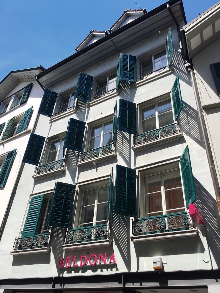 white building with green shutters, 5 stories, decorative balconies, sign reading Beldona
