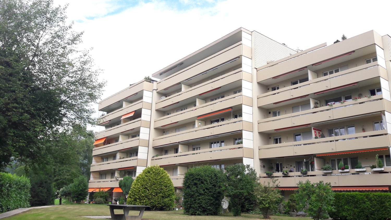 multi-story building, balconies, terrace with awnings, landscaped garden, plants, trees