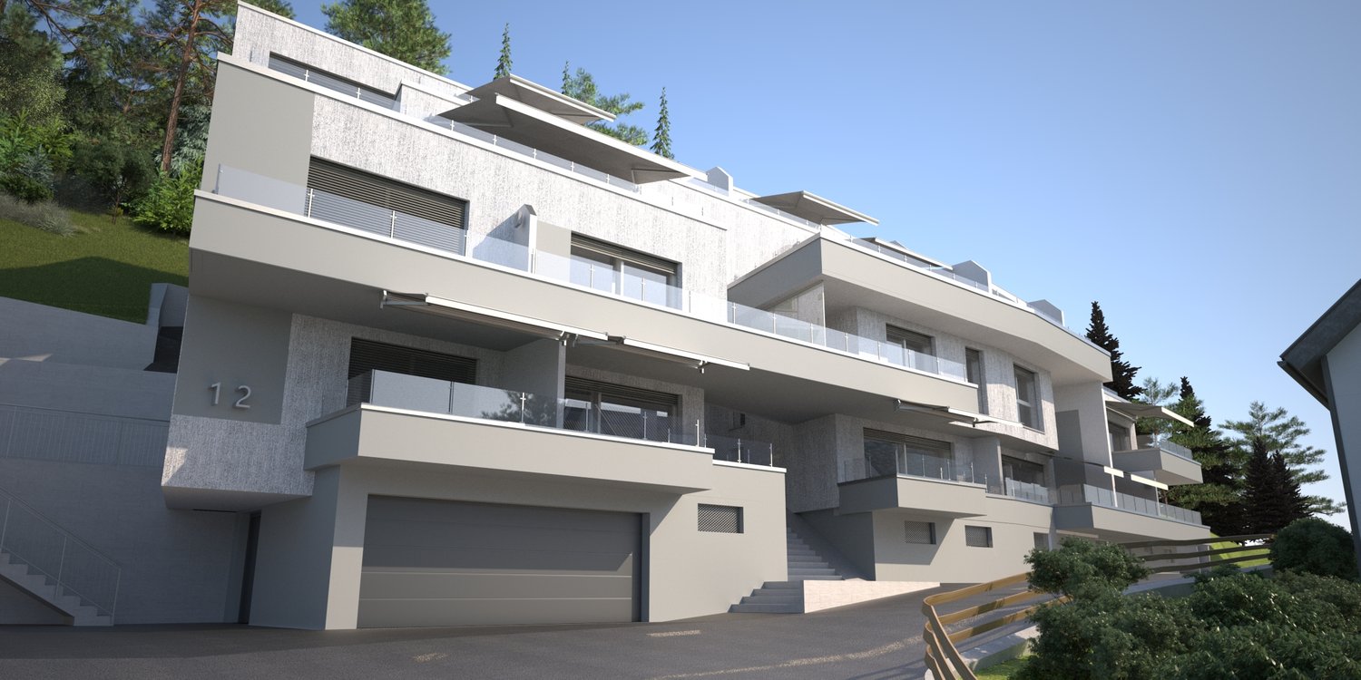 3-story modern apartment building with a gray and white exterior, balconies, and a garage on the ground floor. The building is surrounded by trees and has a sloped driveway leading up to the entrance.