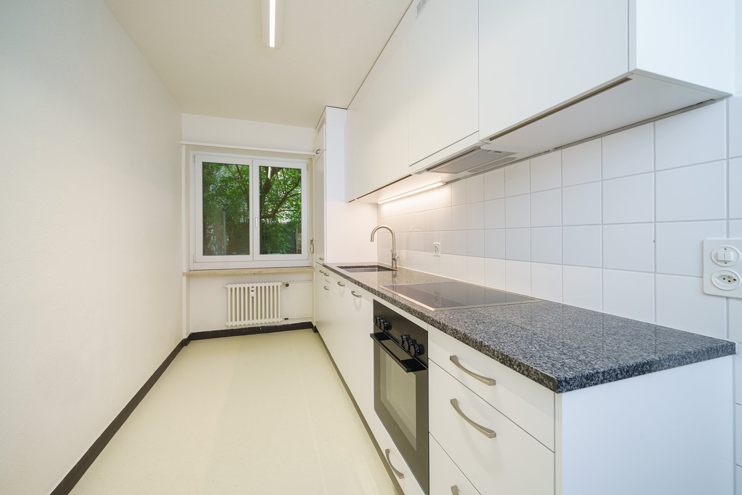 modern kitchen, white cabinets, tile flooring, granite countertop, integrated oven, sink with faucet