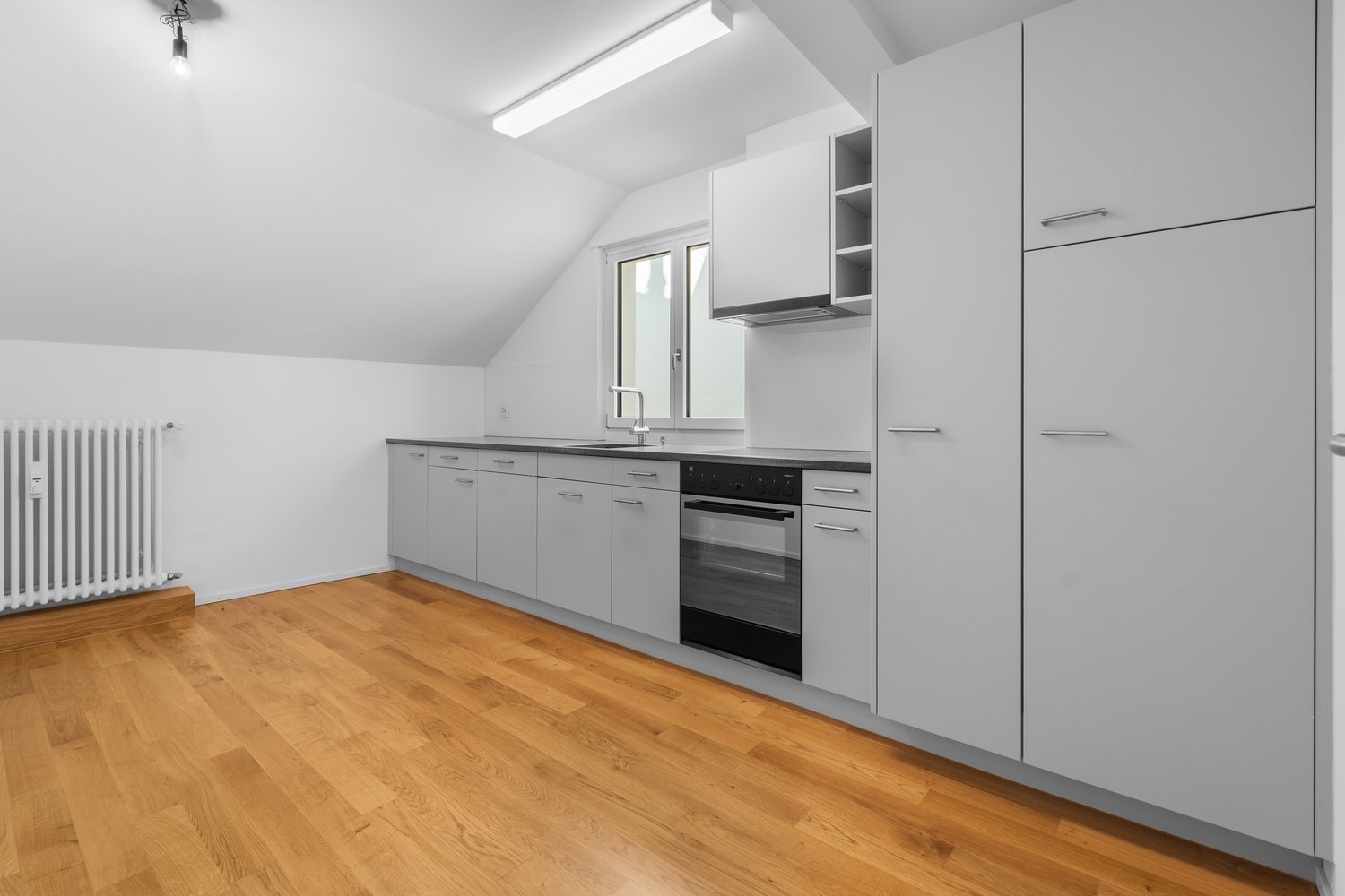 white cabinets, wooden floor, white walls, sink, faucet, radiator, dishwasher, oven