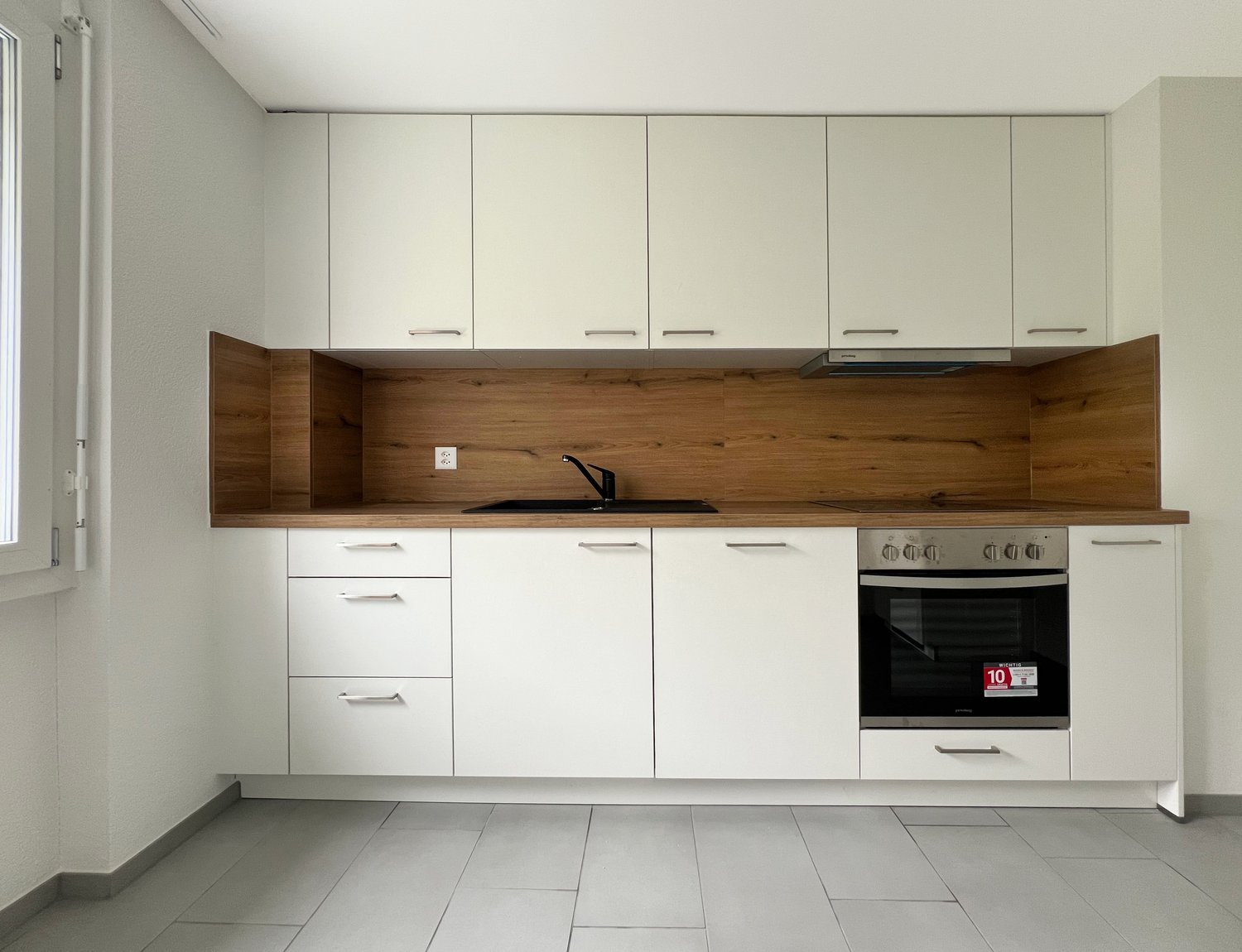white cabinets, wooden countertop, black sink, white stove and oven, white floor