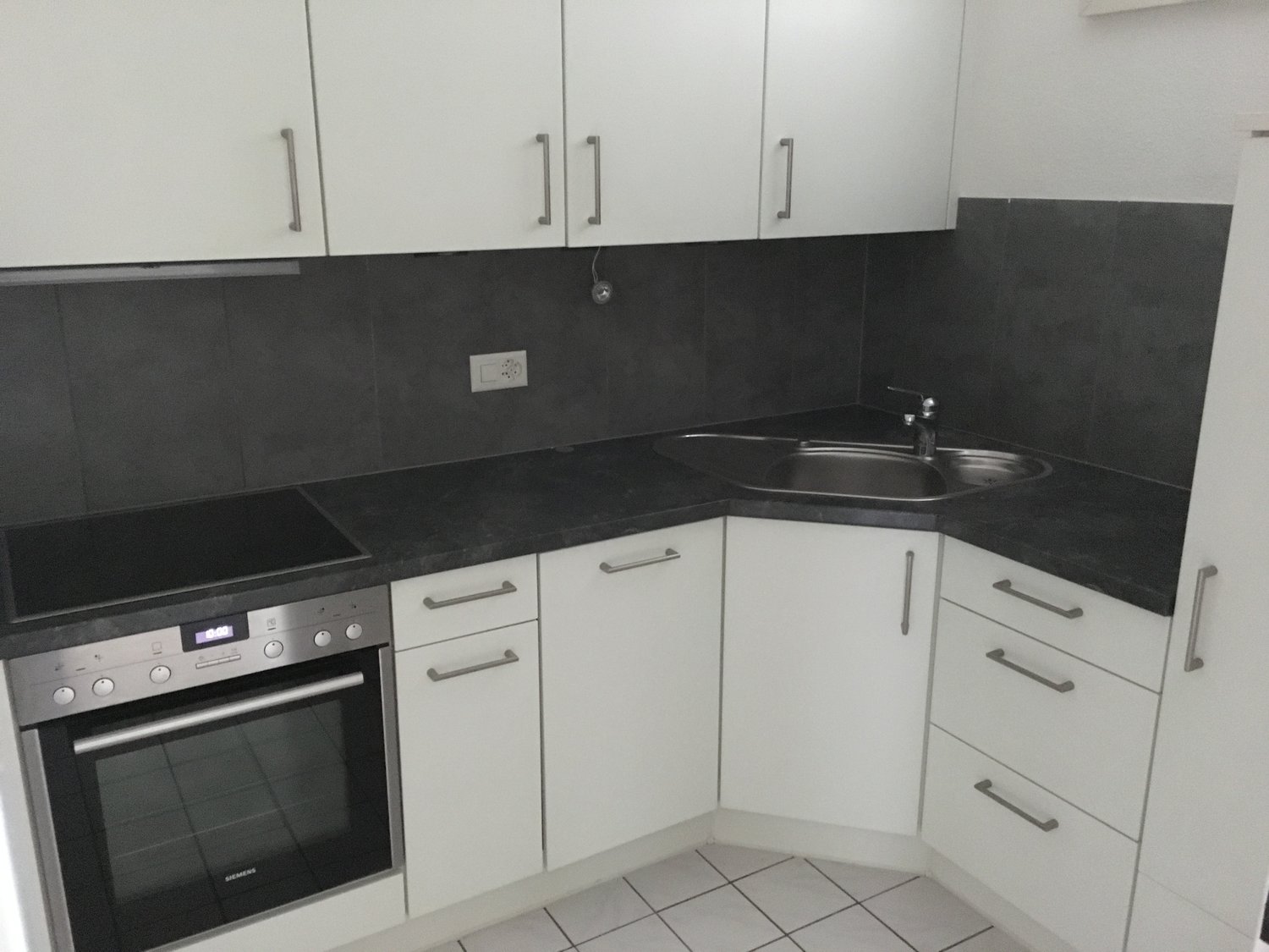 Kitchen with built-in oven, sink with faucet, granite countertop, white cabinets, power outlet, tiled floor