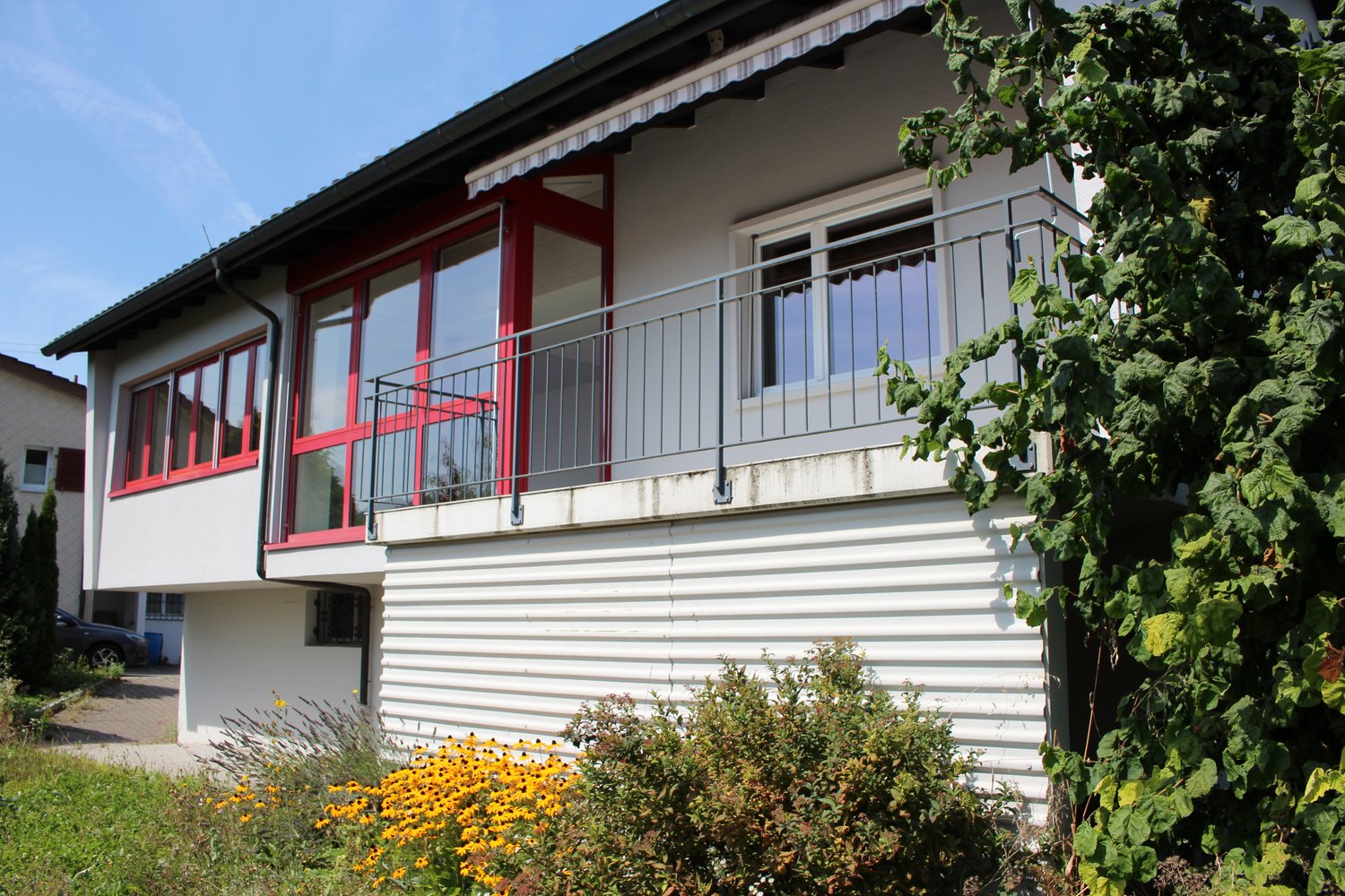2 story house, white wall, red windows, metal balcony railing