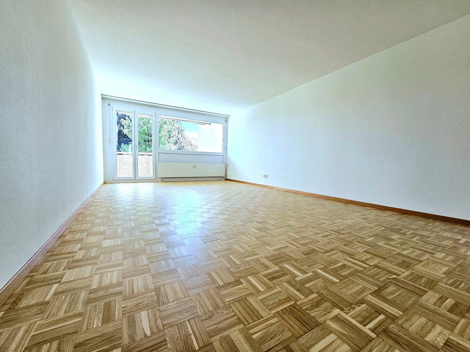 empty room, wooden parquet flooring, white walls, sliding glass door, electrical outlets