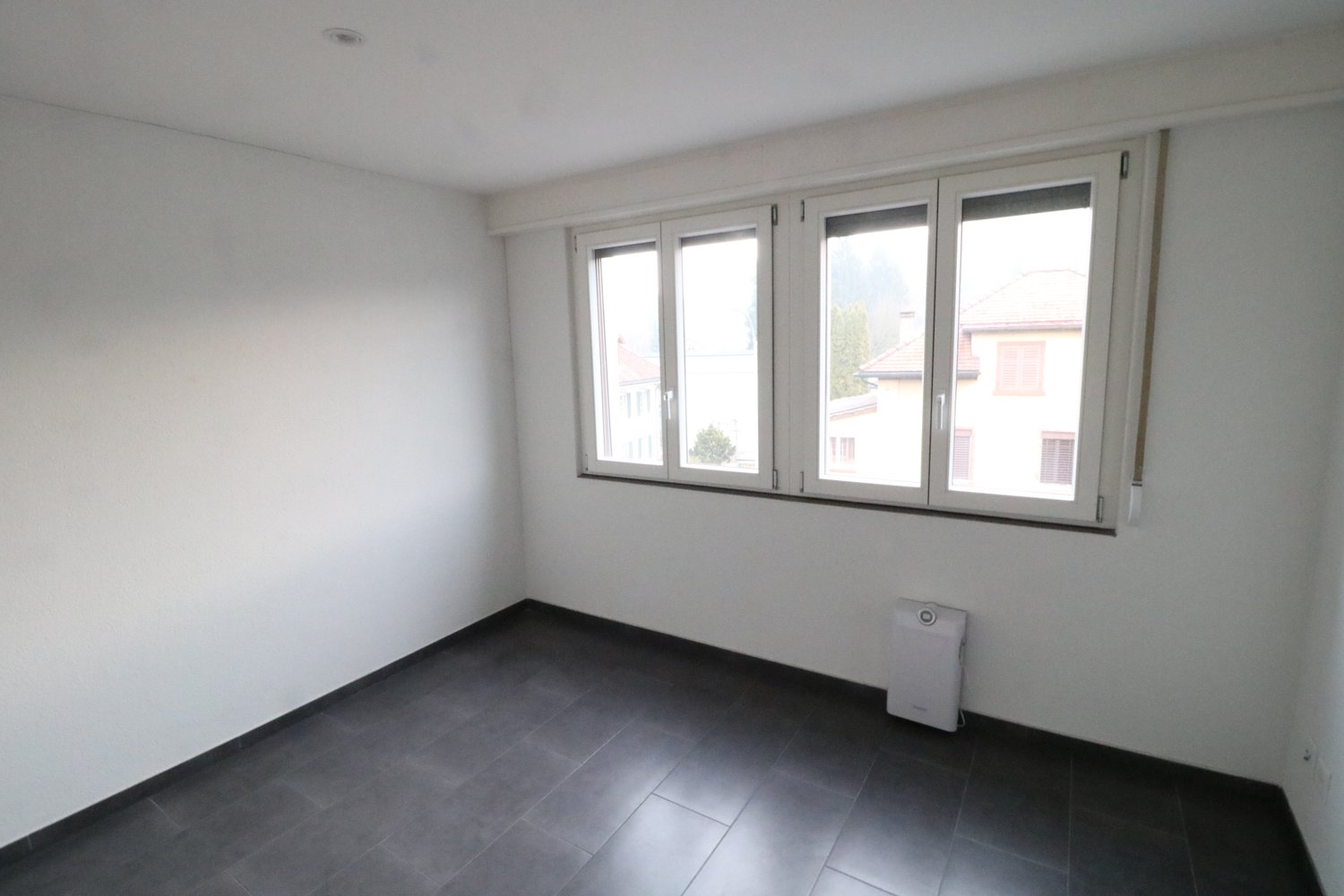 empty room, white walls, black floor tiles, three windows