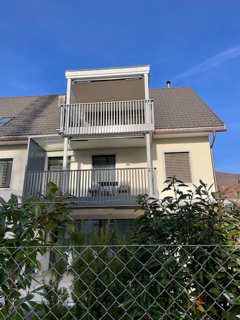 A 2-story house with a terrace, brick walls, and an exterior balcony.