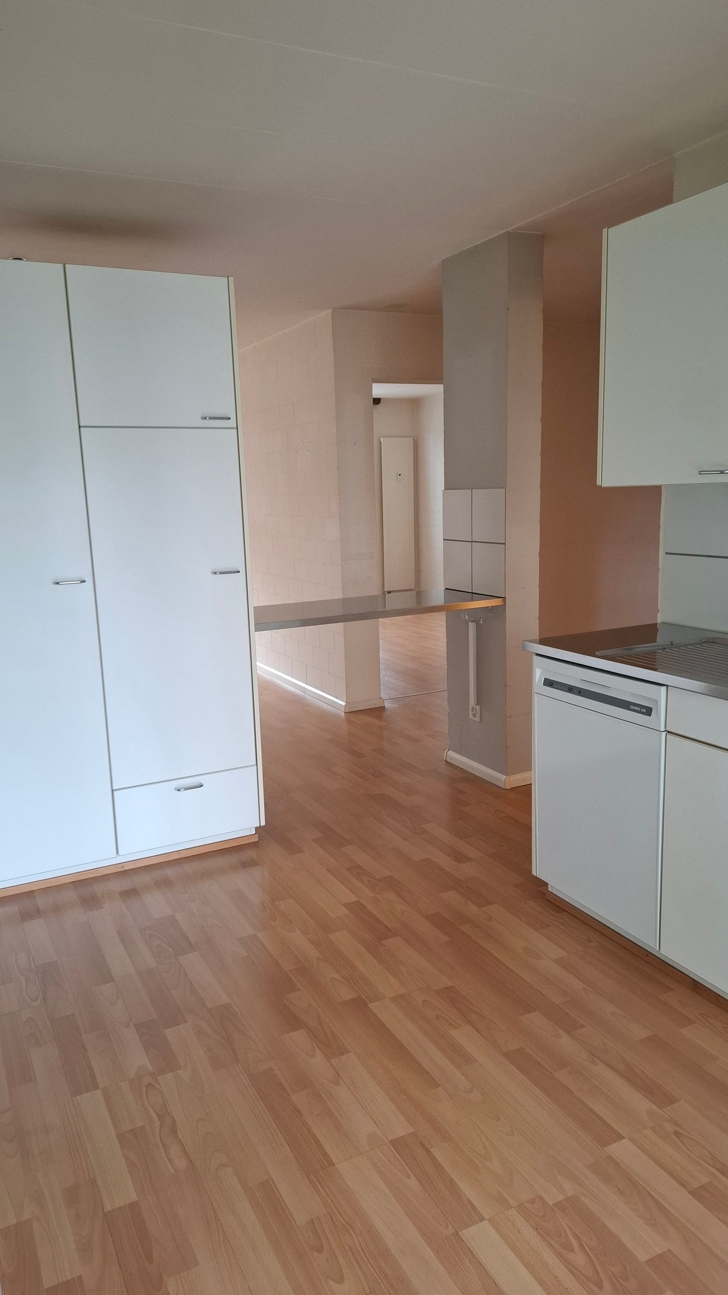 Empty kitchen with wooden floor, kitchen island, built-in appliances, and cabinets