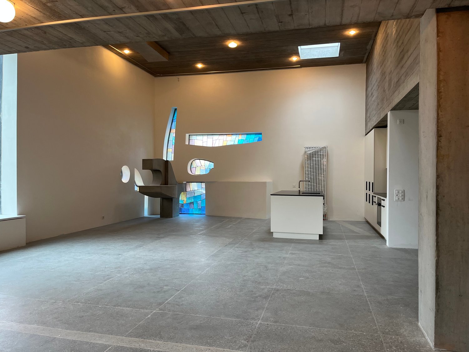 Open floor plan, exposed brick, concrete floor, skylight, large windows, modern kitchen, sink and faucet