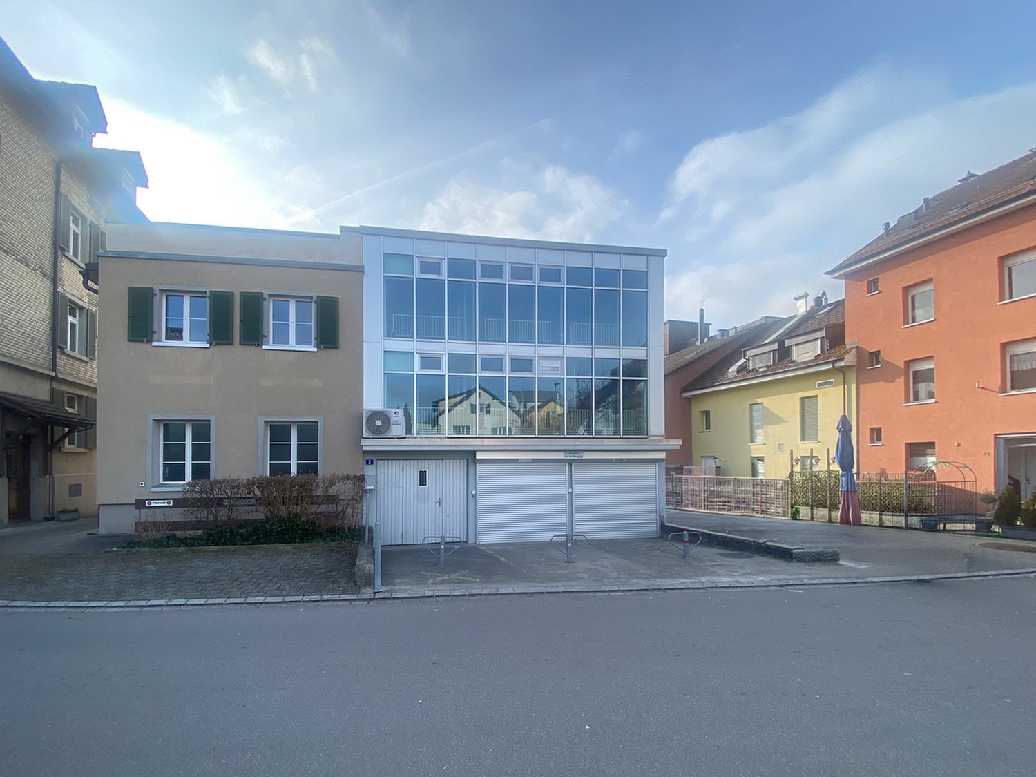 3-story building with a garage in front and glass windows.