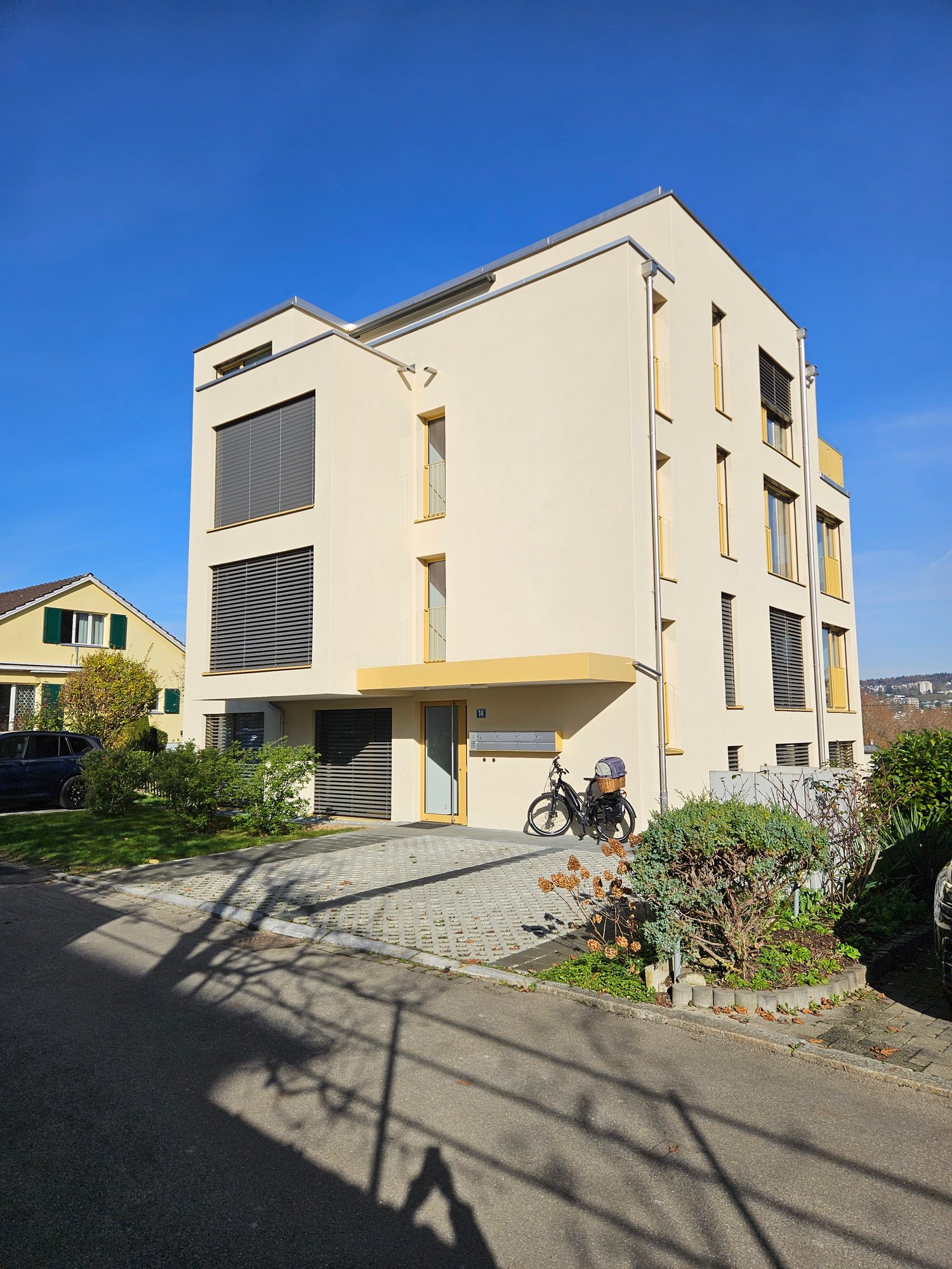 modern house, beige, 3 stories, multiple windows, entrance door, bicycle in front