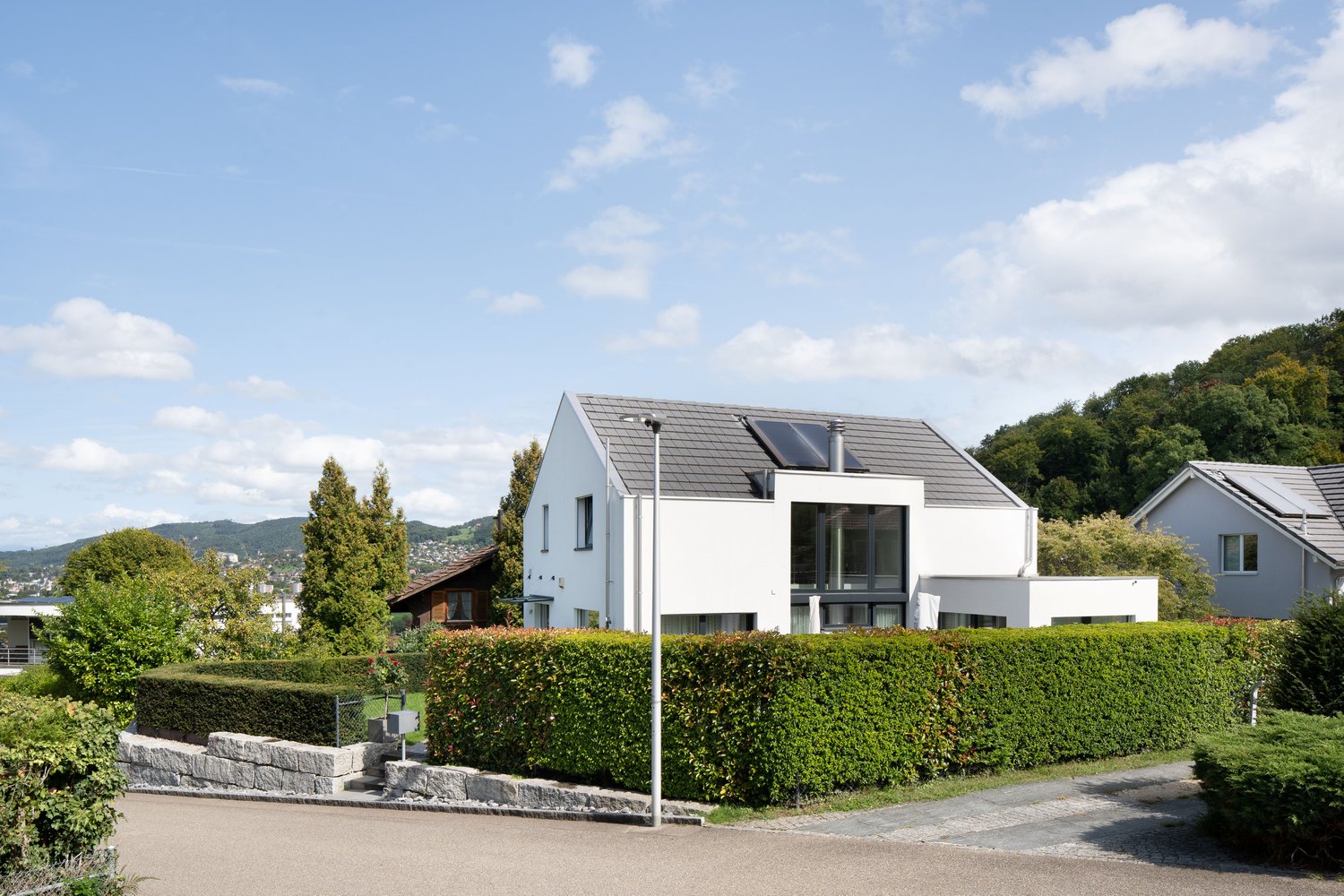 Modern white house, gray roof, solar panels, terrace, well-kept garden