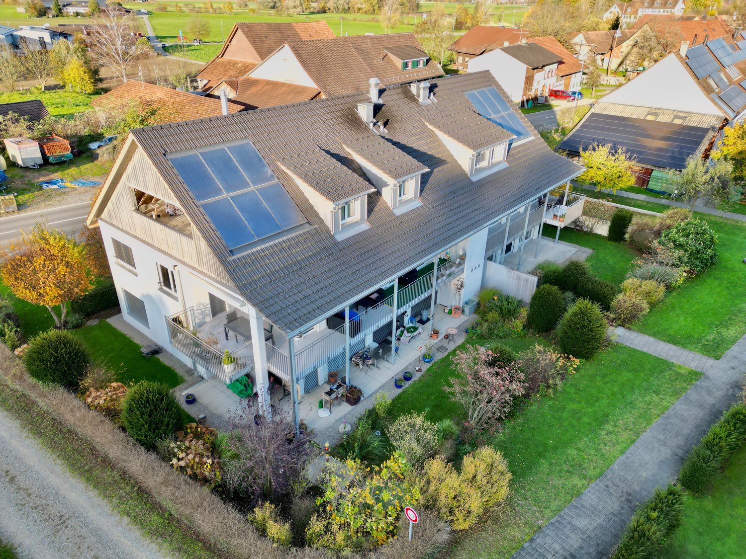 3 story house, solar panels, gray roof, white walls, balconies, garden