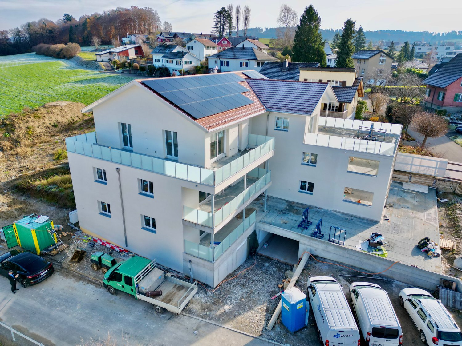 Apt building: 3 stories, solar panels, multiple balconies, underground parking garage
