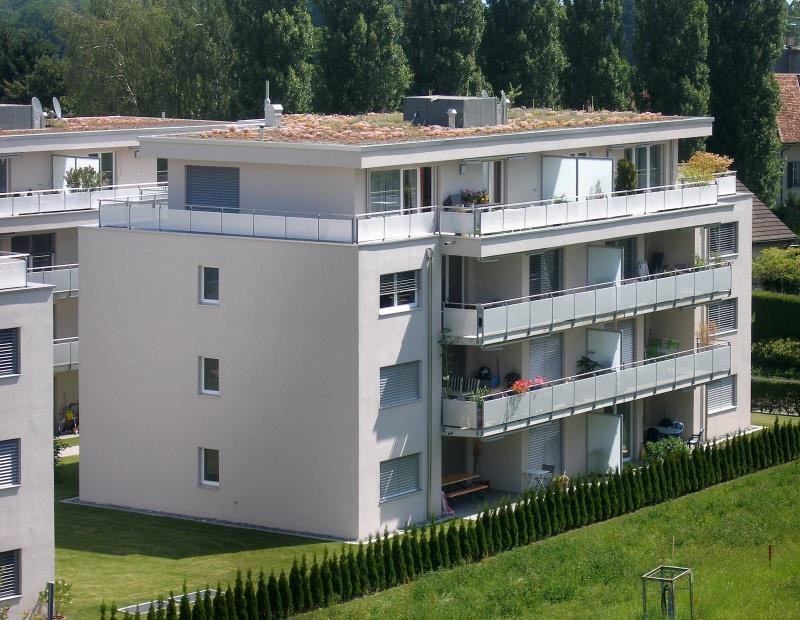 4 story building, white walls, large windows, metal fences, balcony