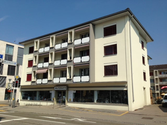 white building with balconies, store at the street level, multiple floors