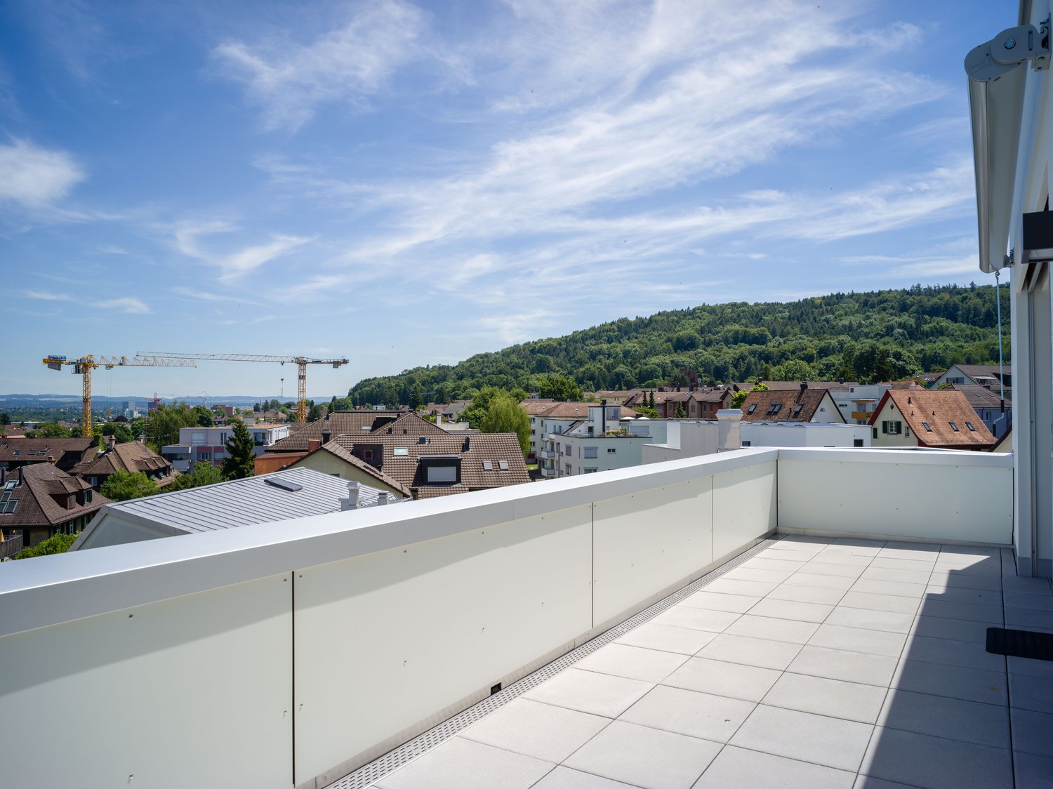 rooftop terrace, white tiled floor, white railing, view of city, crane in distance