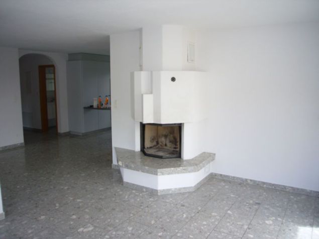 Empty room with white walls, tiled floor, and a central fireplace with a granite surround.
