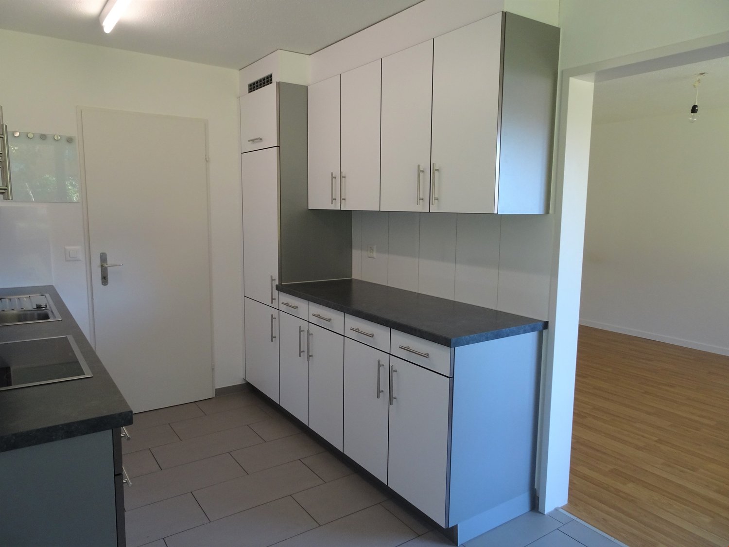 modern white kitchen, black countertop, under-mount sink, dishwasher, electrical outlet, wooden floor
