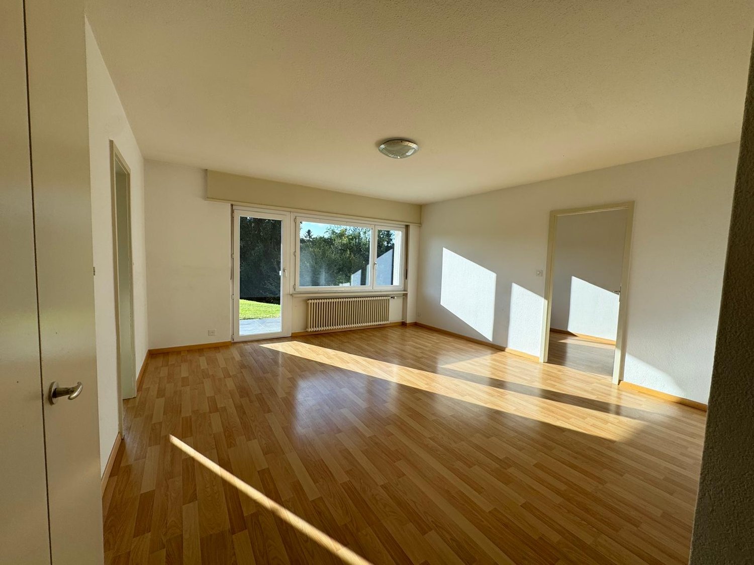 large windows, wooden floor, white walls, glass door leading to outside