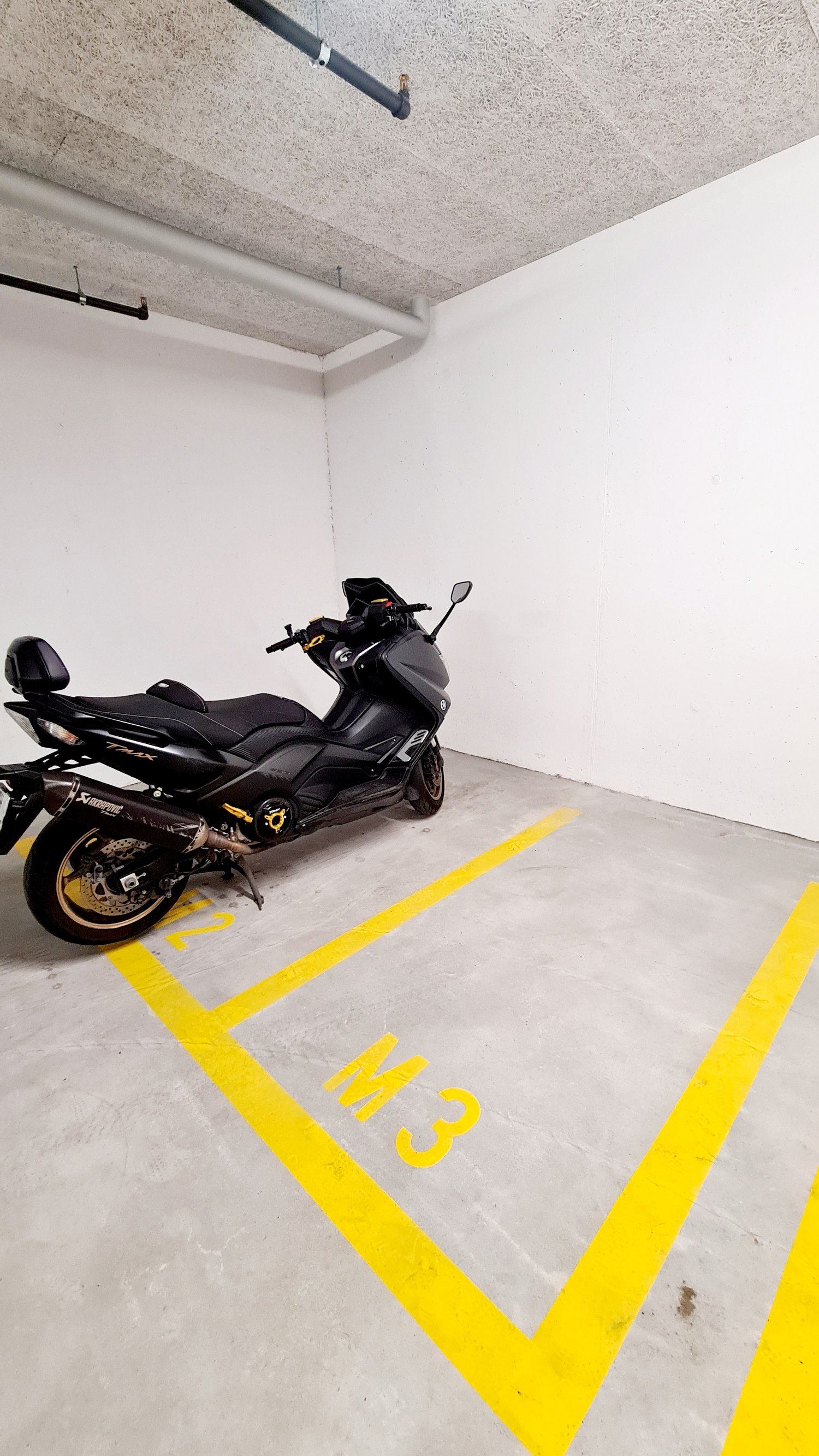 Empty parking space with yellow markings, a black motorcycle parked in it