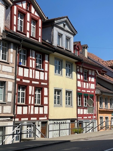 Traditional German house, yellow exterior with red trim, multiple floors, multiple windows, multiple doors, chimney