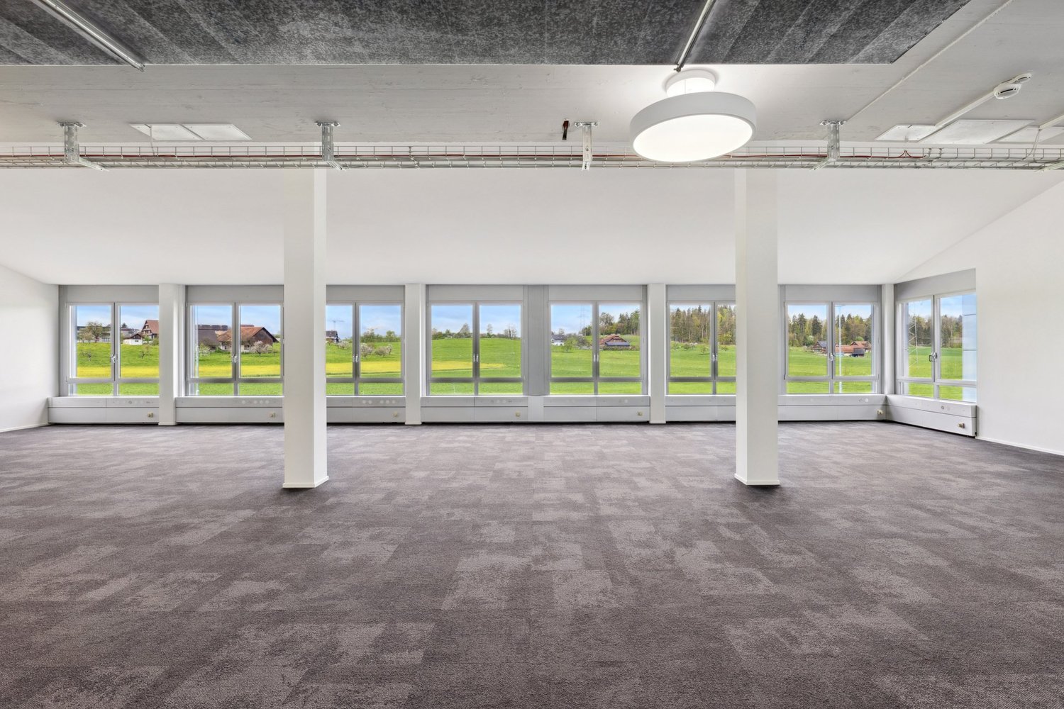 large open room, high ceilings, large windows, gray flooring, large view to the outside