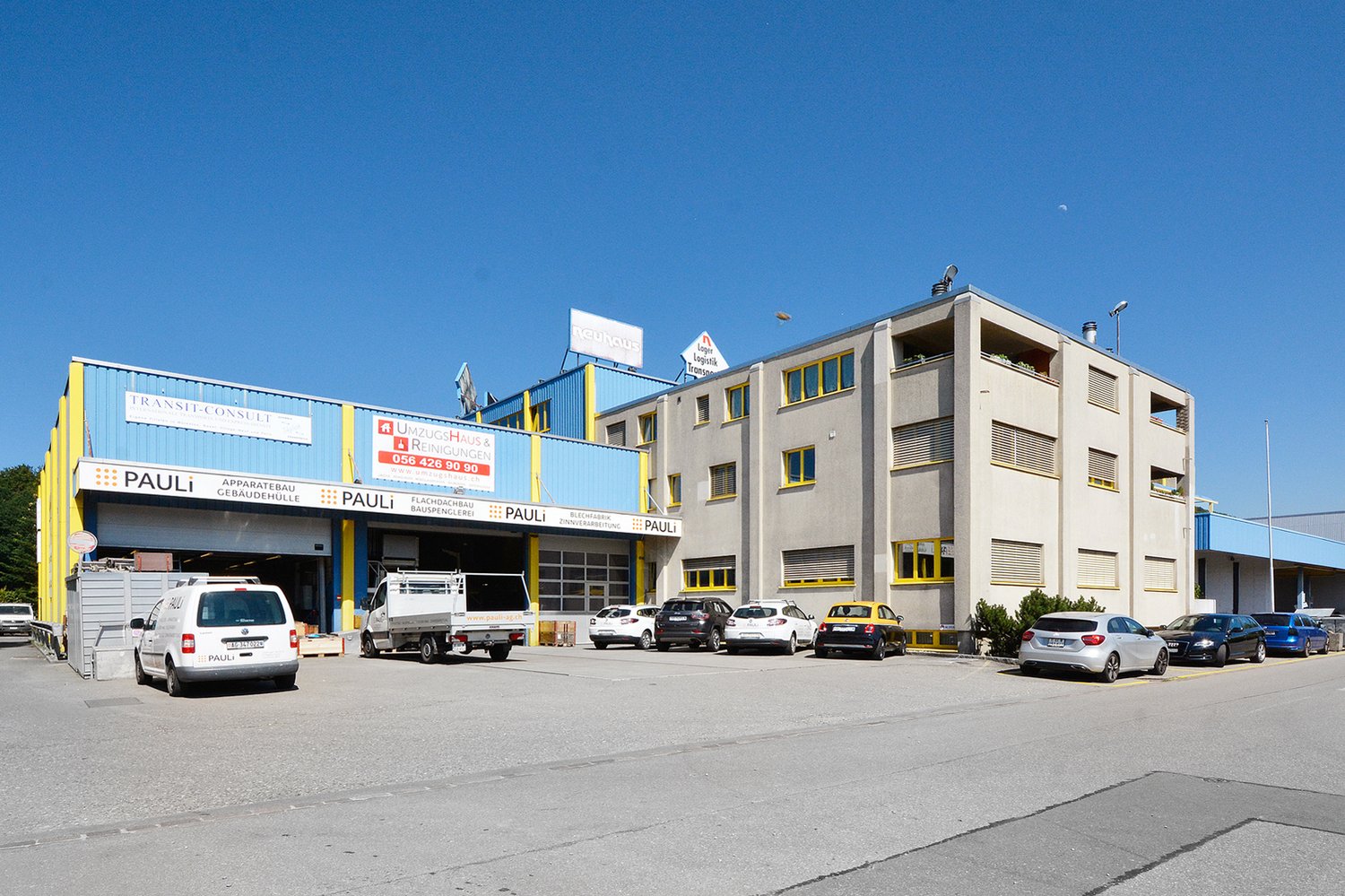 Large commercial building with multiple entrances and many cars parked in the parking lot