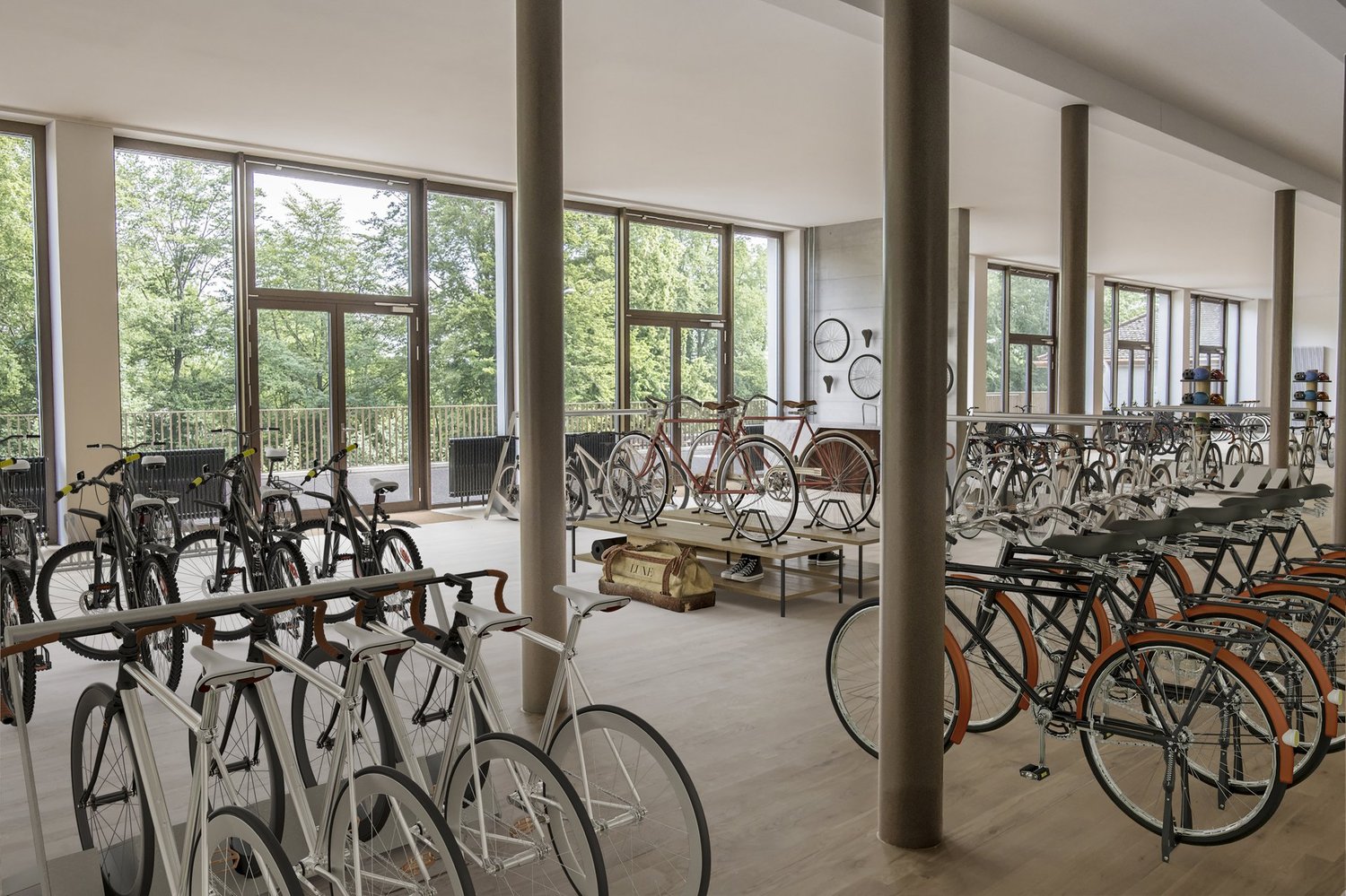 large room with many bicycles parked, wooden floor, large windows, metal poles, tables with bags