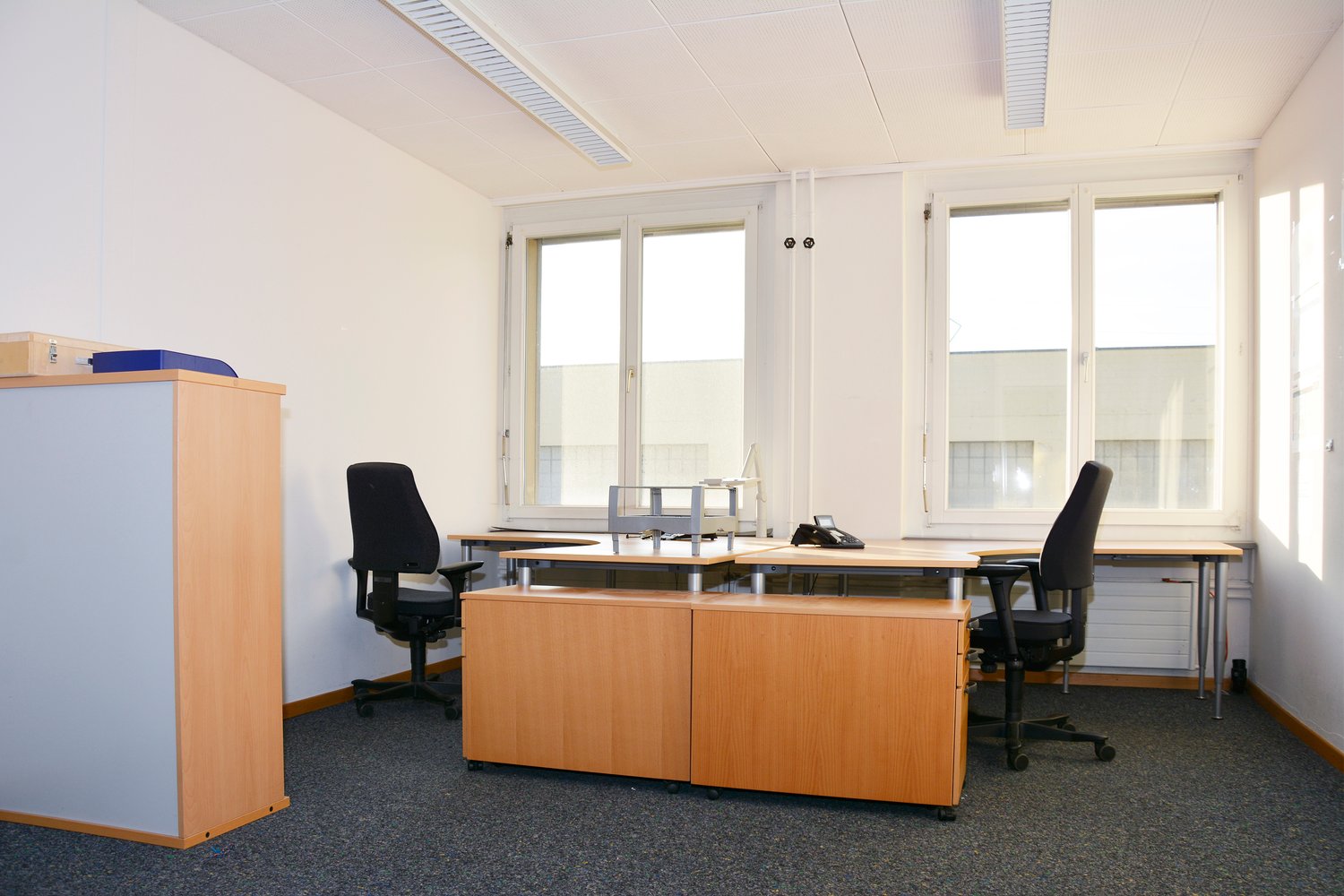 Empty office room, with three desks, two chairs, and cabinets