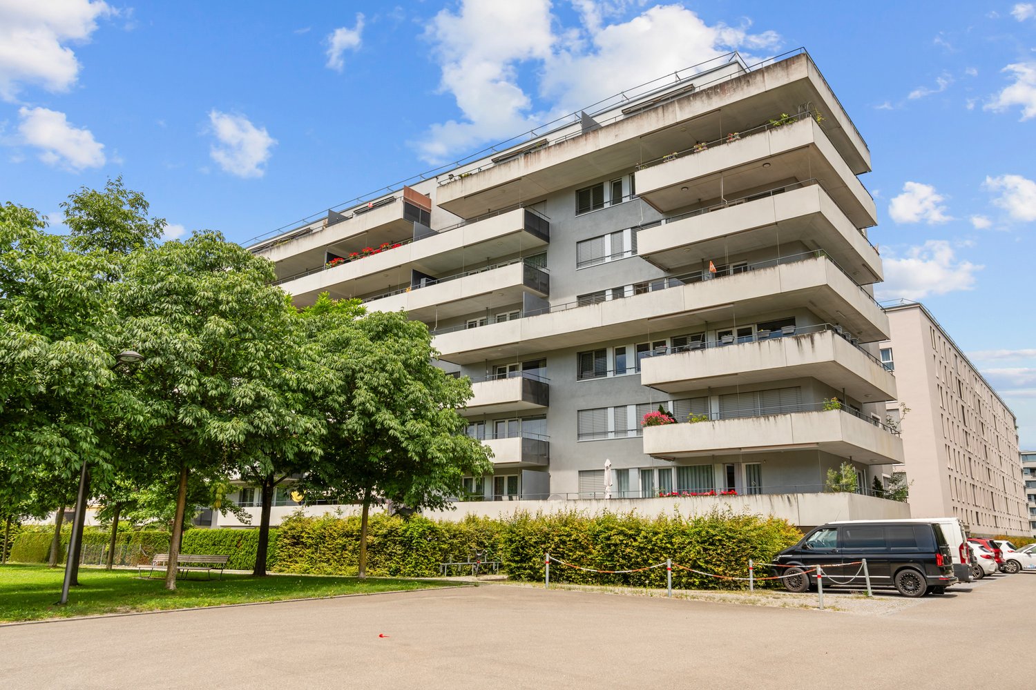 apartment building, balconies, multiple floors, outdoor area, cars parked